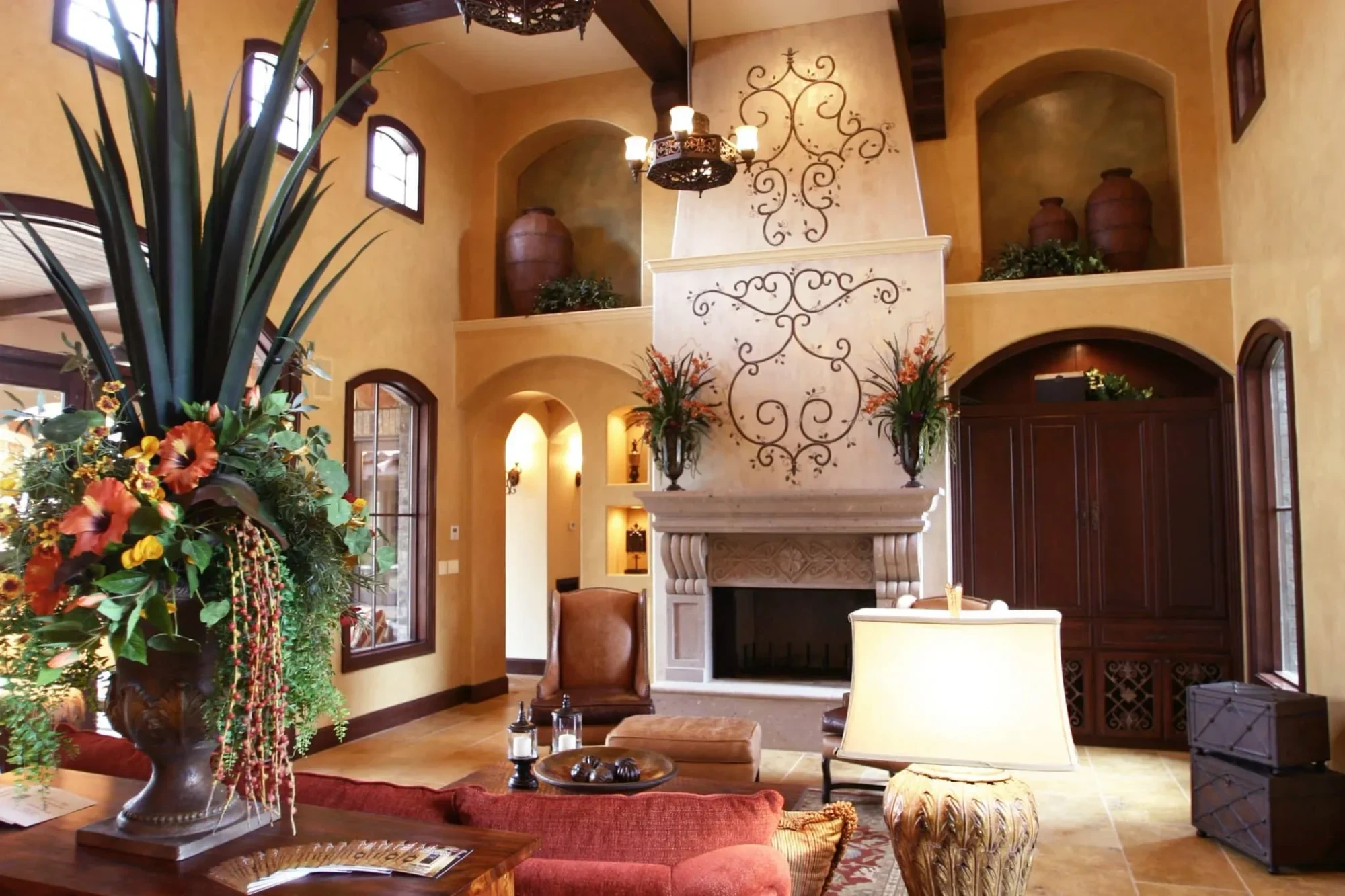 Tall living room fireplace with scrolled iron wall decor and arched niches, Mediterranean Parade Home