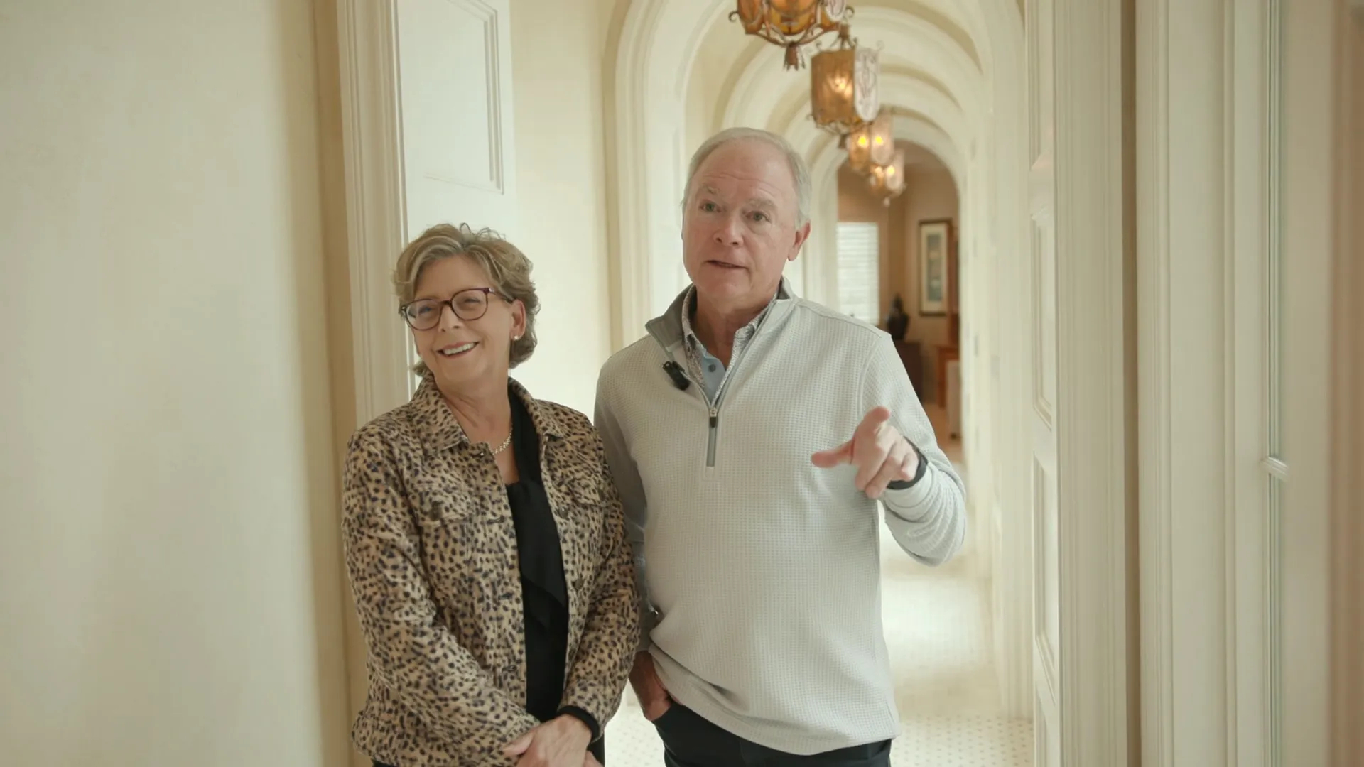 A couple smiling side by side in an arched hallway