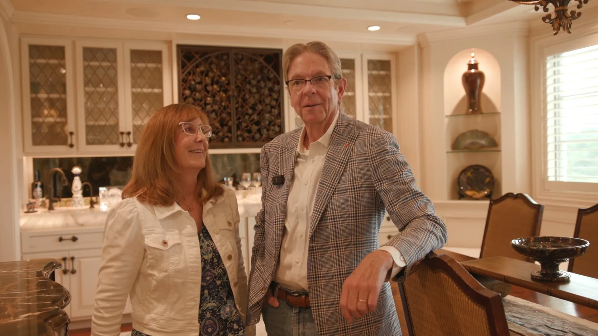 A couple standing in their dining room by the wine bar