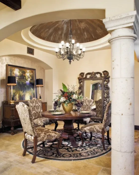 Round dining table under a domed ceiling with chandelier beside a stone column, Mediterranean Parade Home