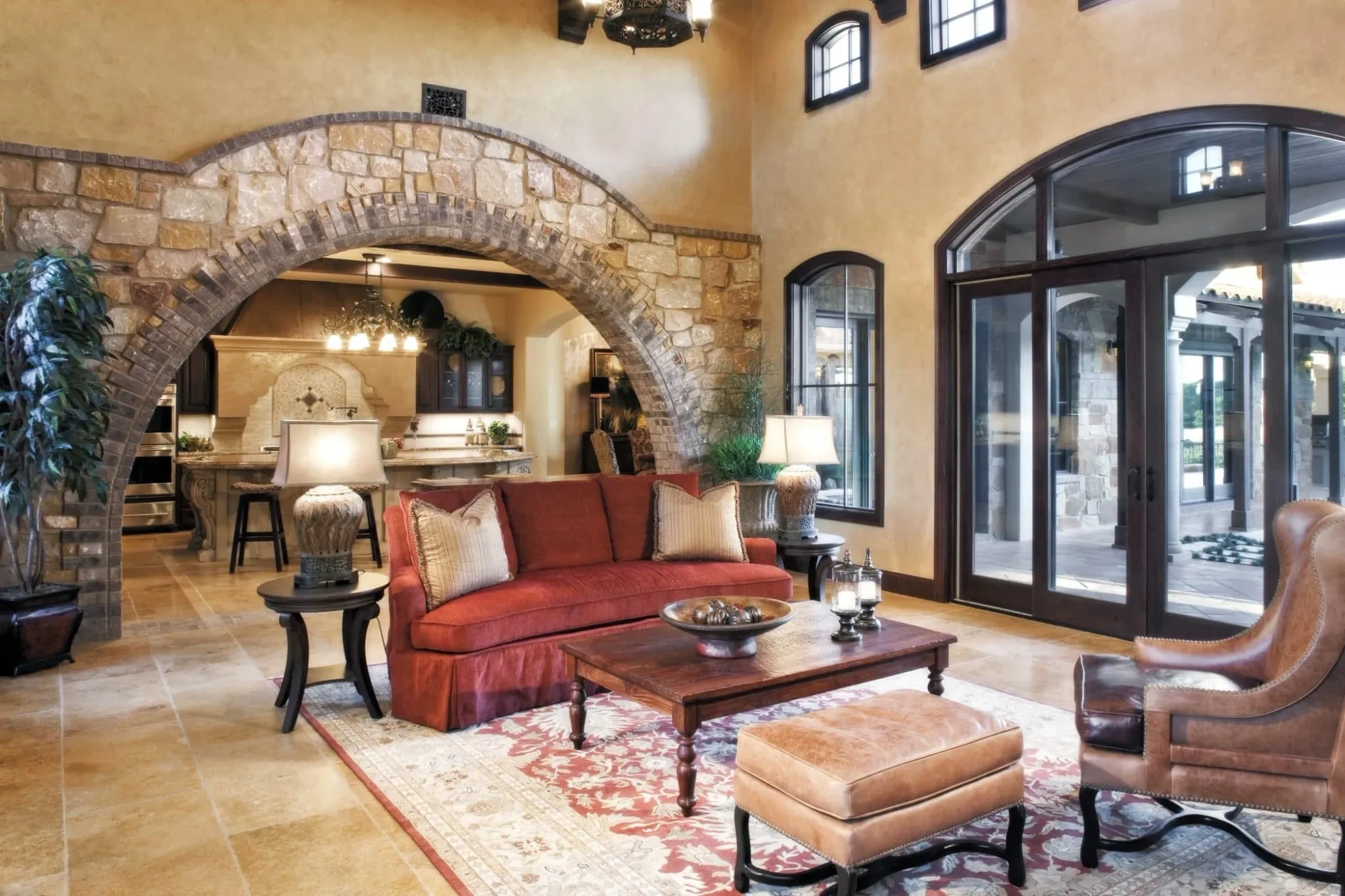 Living room with red sofa, stone and brick arch and arched glass doors, Mediterranean Parade Home