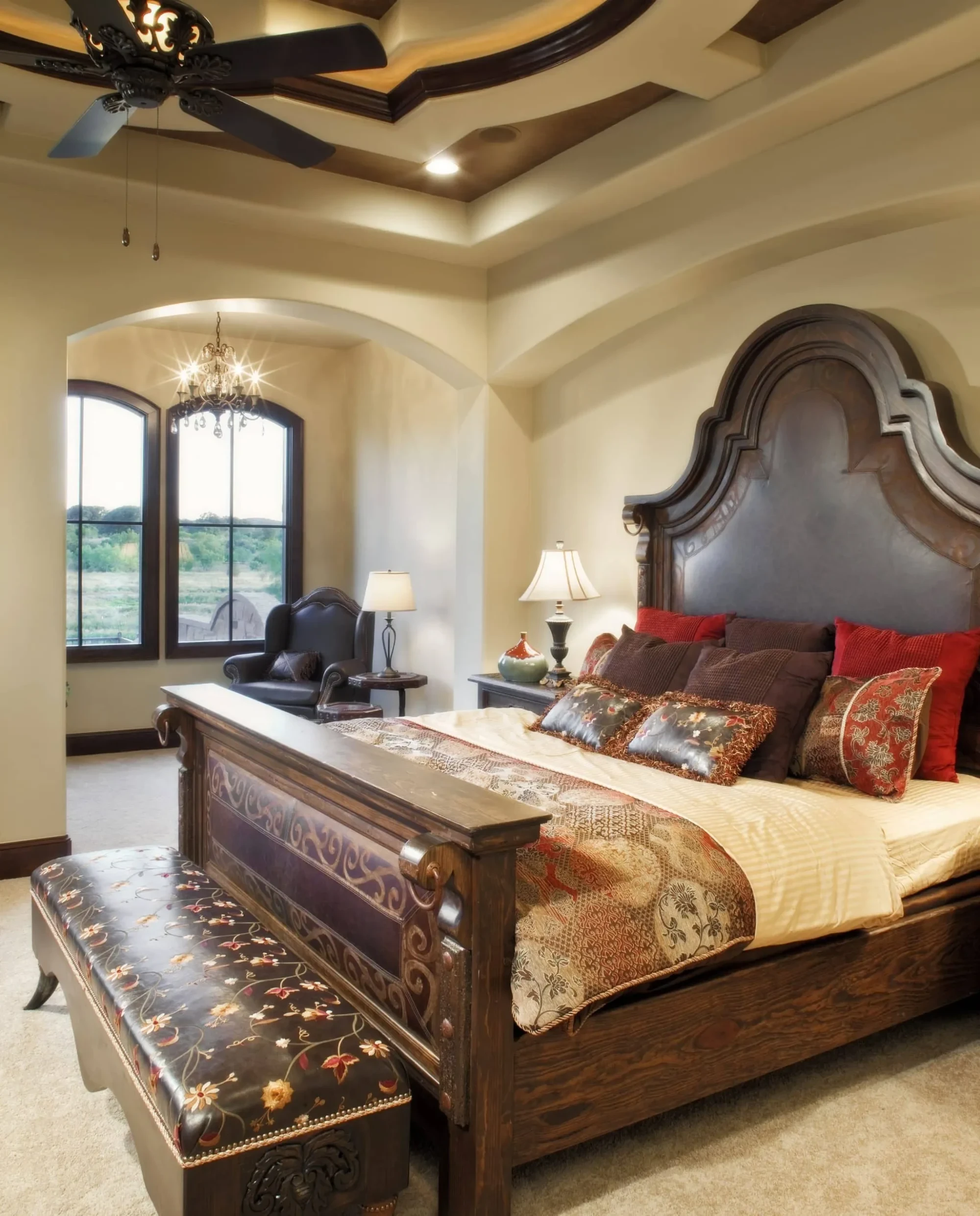 Bedroom with tall carved headboard, stepped tray ceiling and arched windows, Mediterranean Parade Home