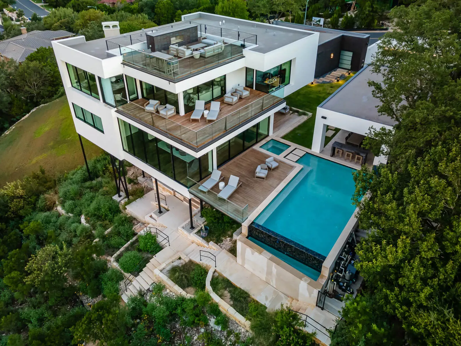 Aerial view of a modern hillside home in Austin with stacked decks and infinity pool
