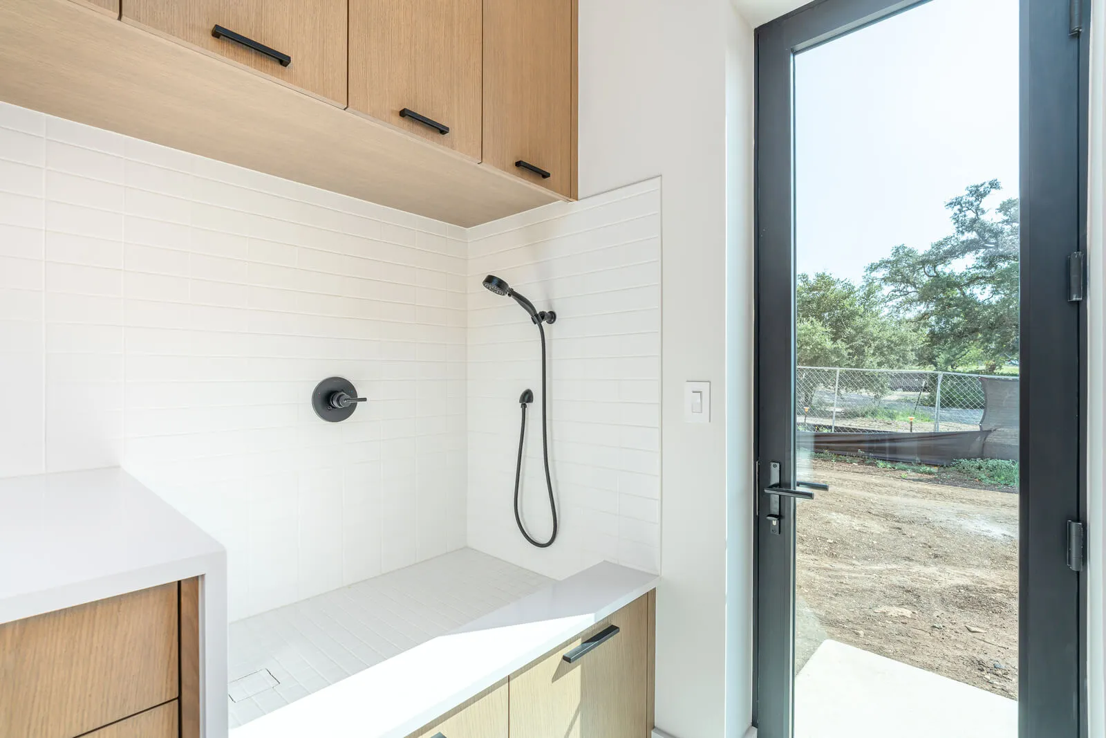 White tile dog-wash with handheld sprayer beside patio door.
