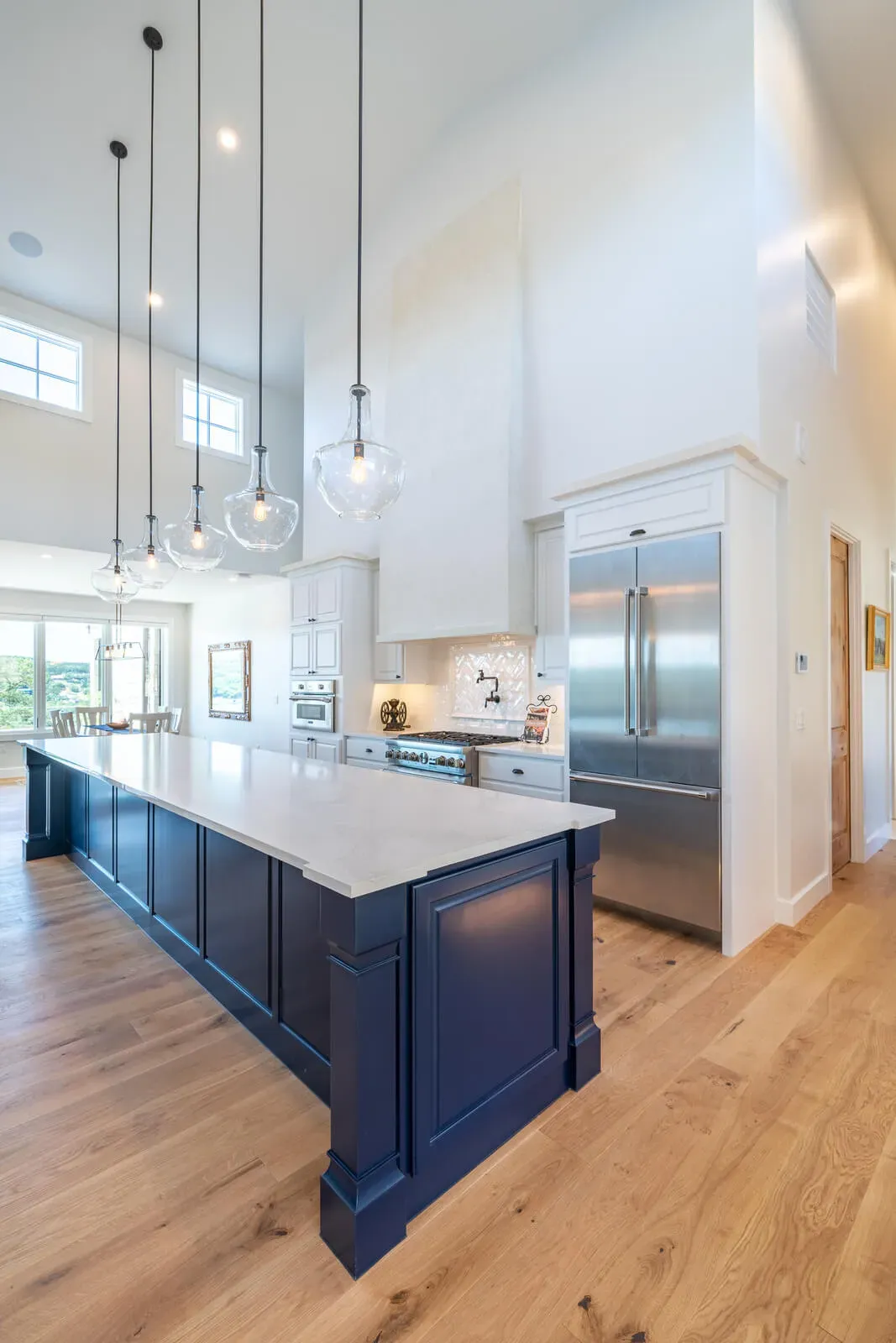 Spacious kitchen with navy blue island and pendant lighting