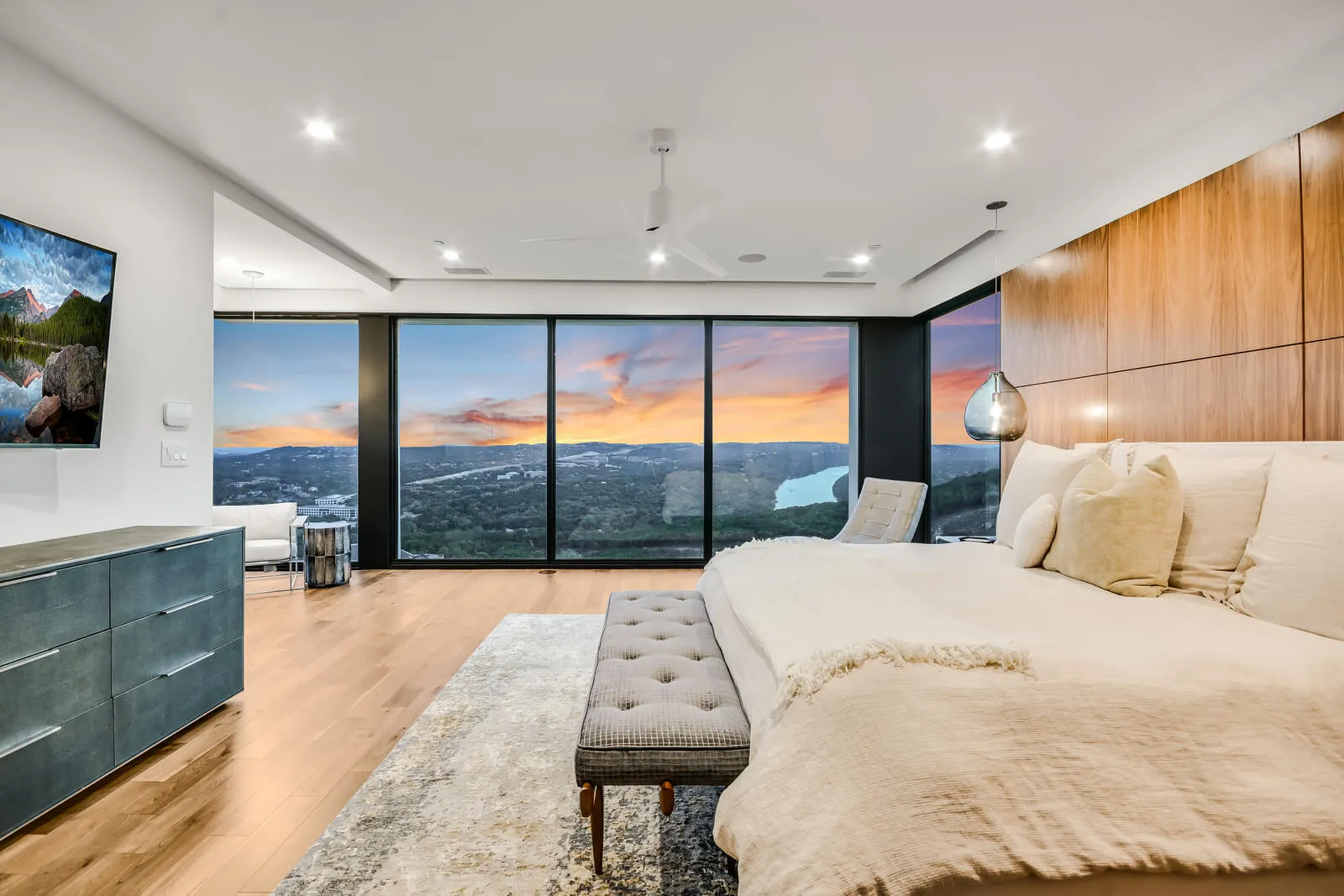Luxury Austin bedroom with panoramic glass wall overlooking Hill Country