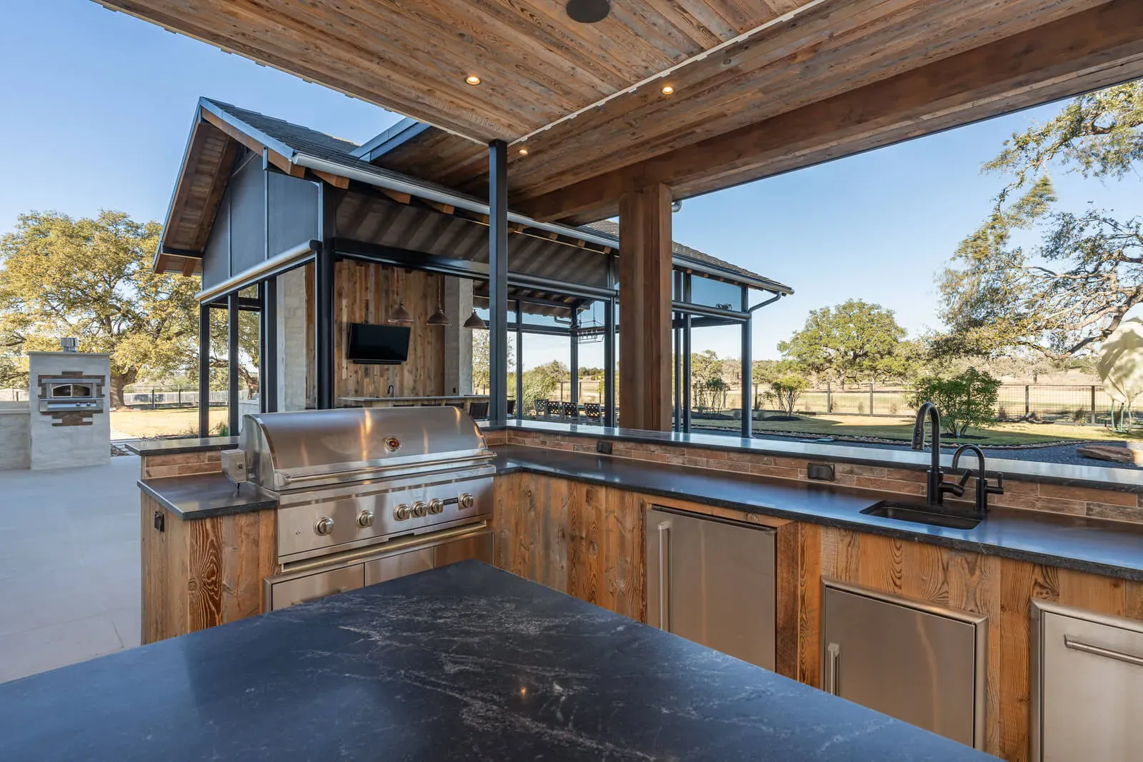 Outdoor kitchen with stainless grill and Hill Country views in an Austin luxury home.