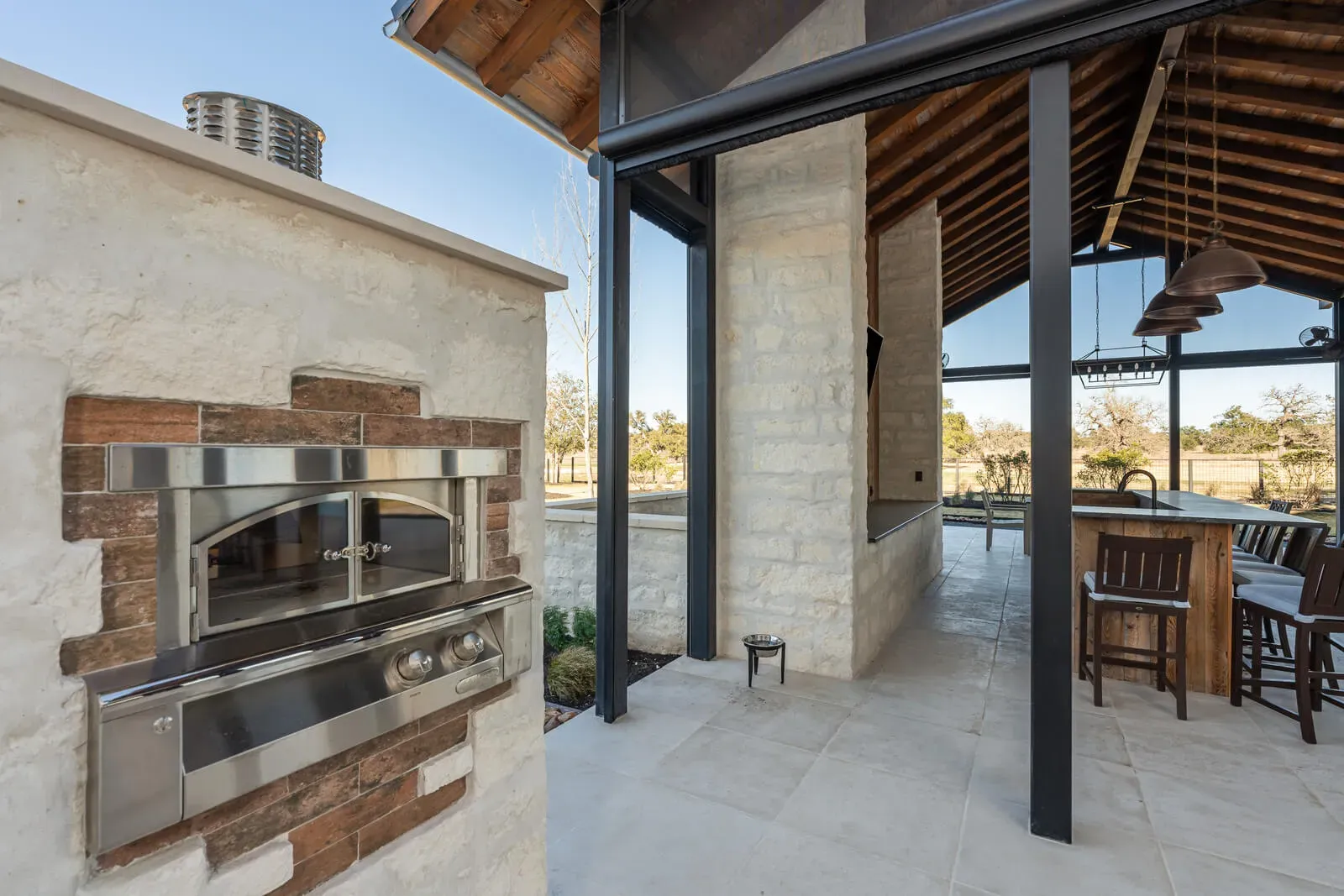 Built-in outdoor pizza oven surrounded by stonework in a Hill Country luxury home.