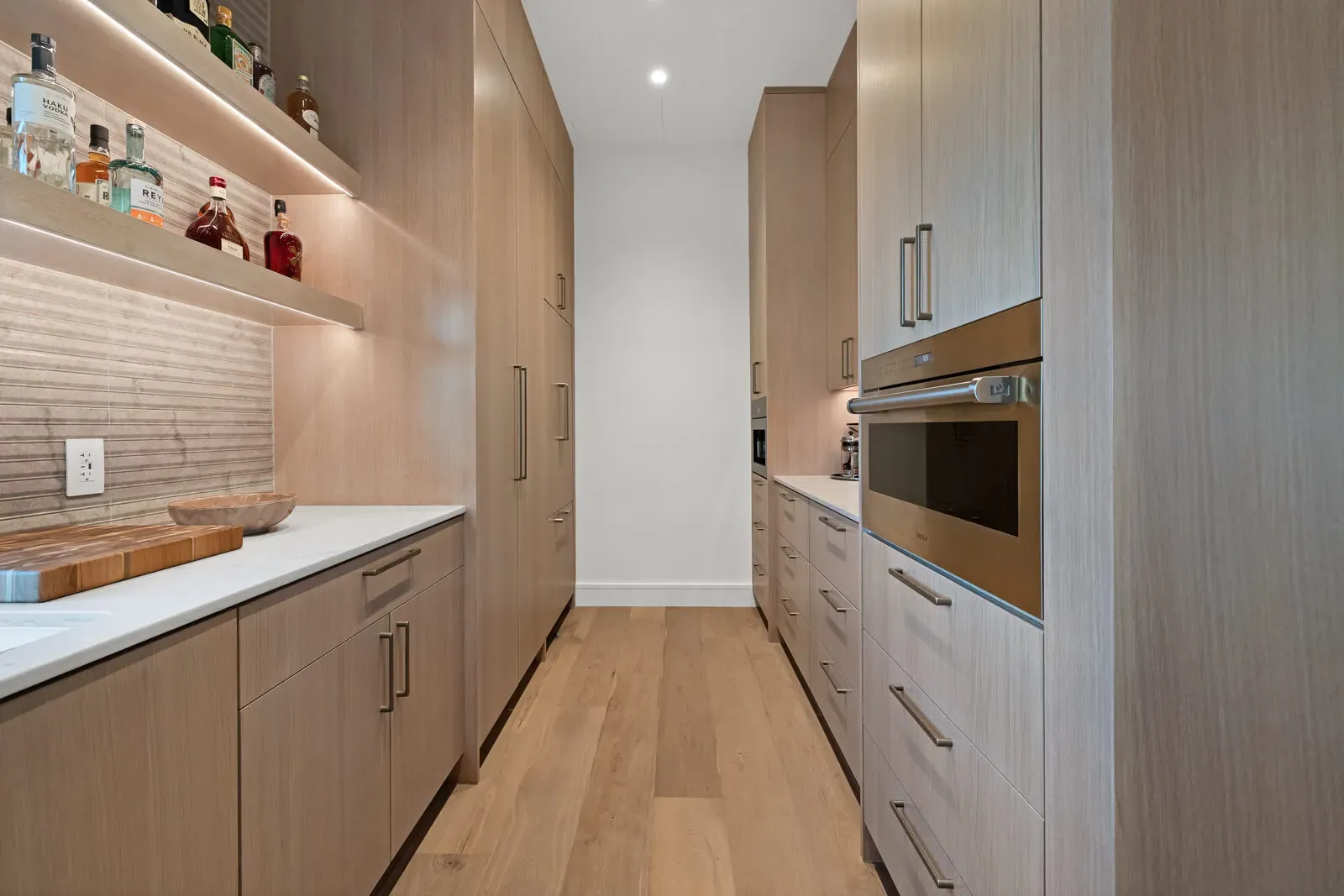 Hidden scullery kitchen with beverage storage, secondary oven, and concealed cabinetry