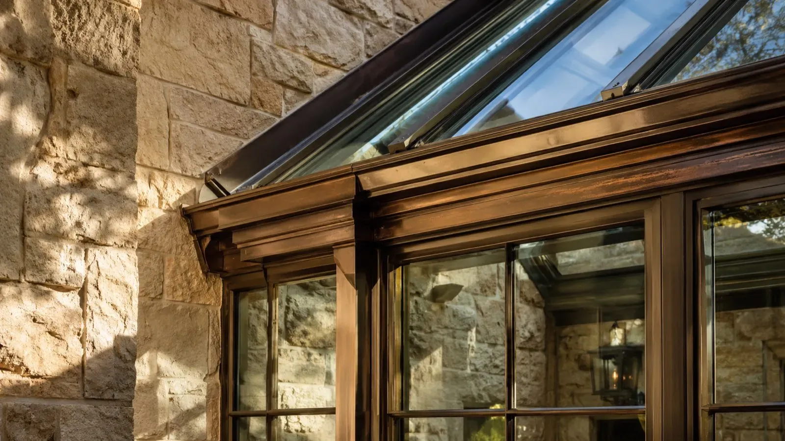 Bronze-framed glazing detail at a conservatory roof transition, showing flashing and water-management detailing.