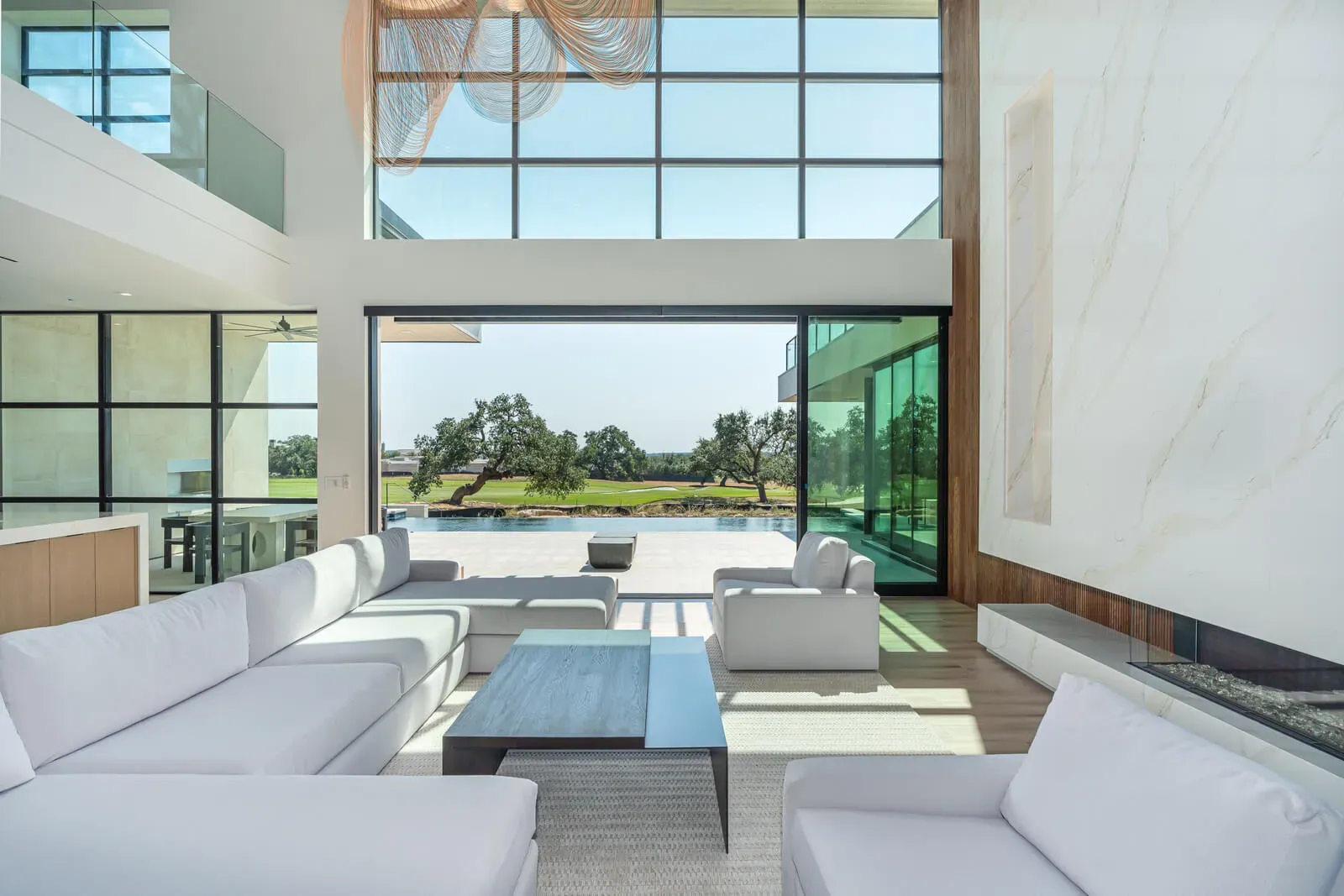 Contemporary Austin living space with tall window wall opening to outdoor pool and landscape.