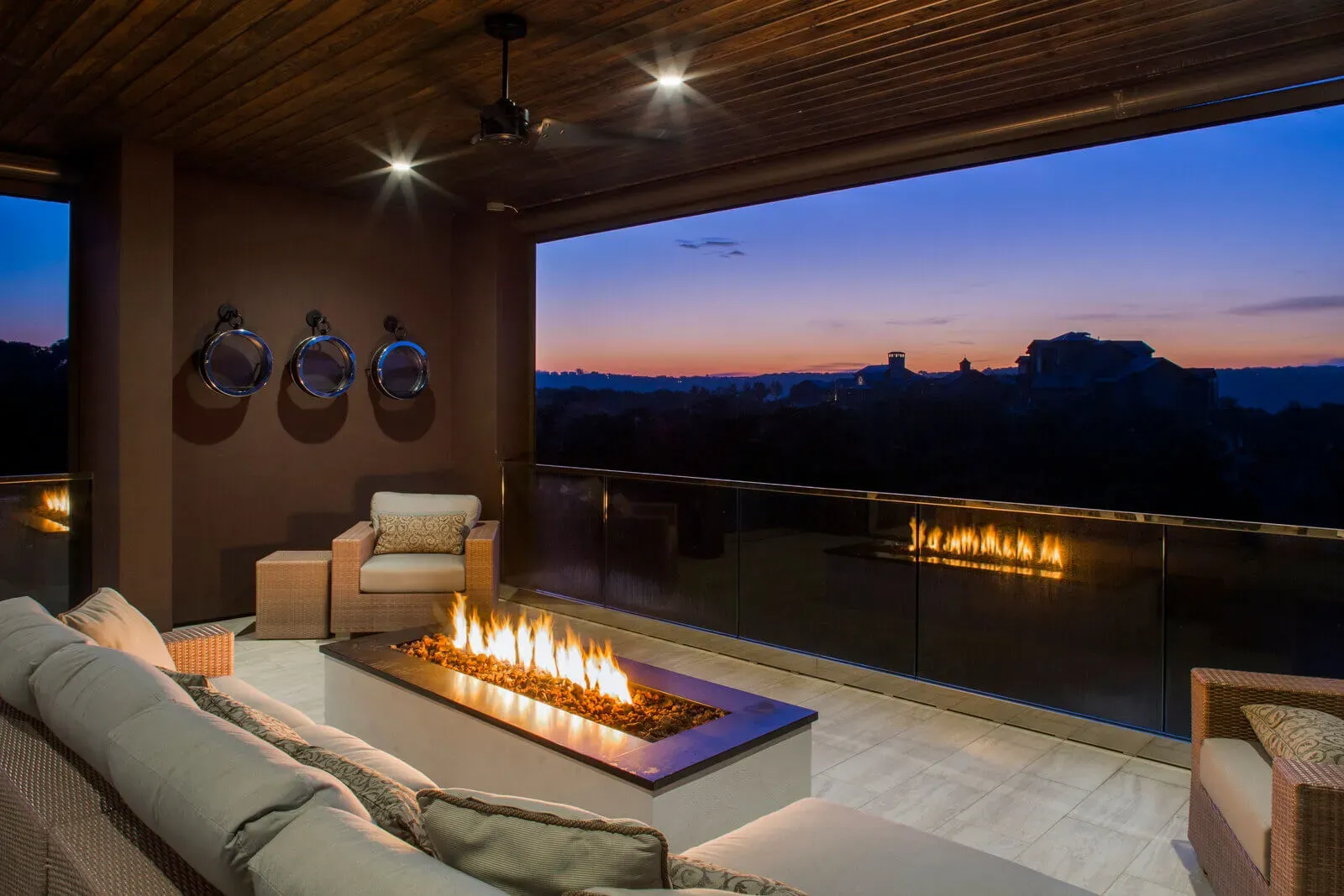 Covered outdoor lounge with linear fire feature and Hill Country dusk views
