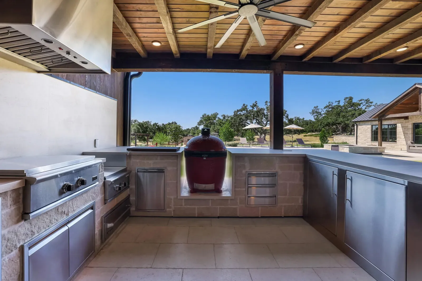 Covered outdoor kitchen featuring a Kamado smoker and stainless appliances in an Austin home.
