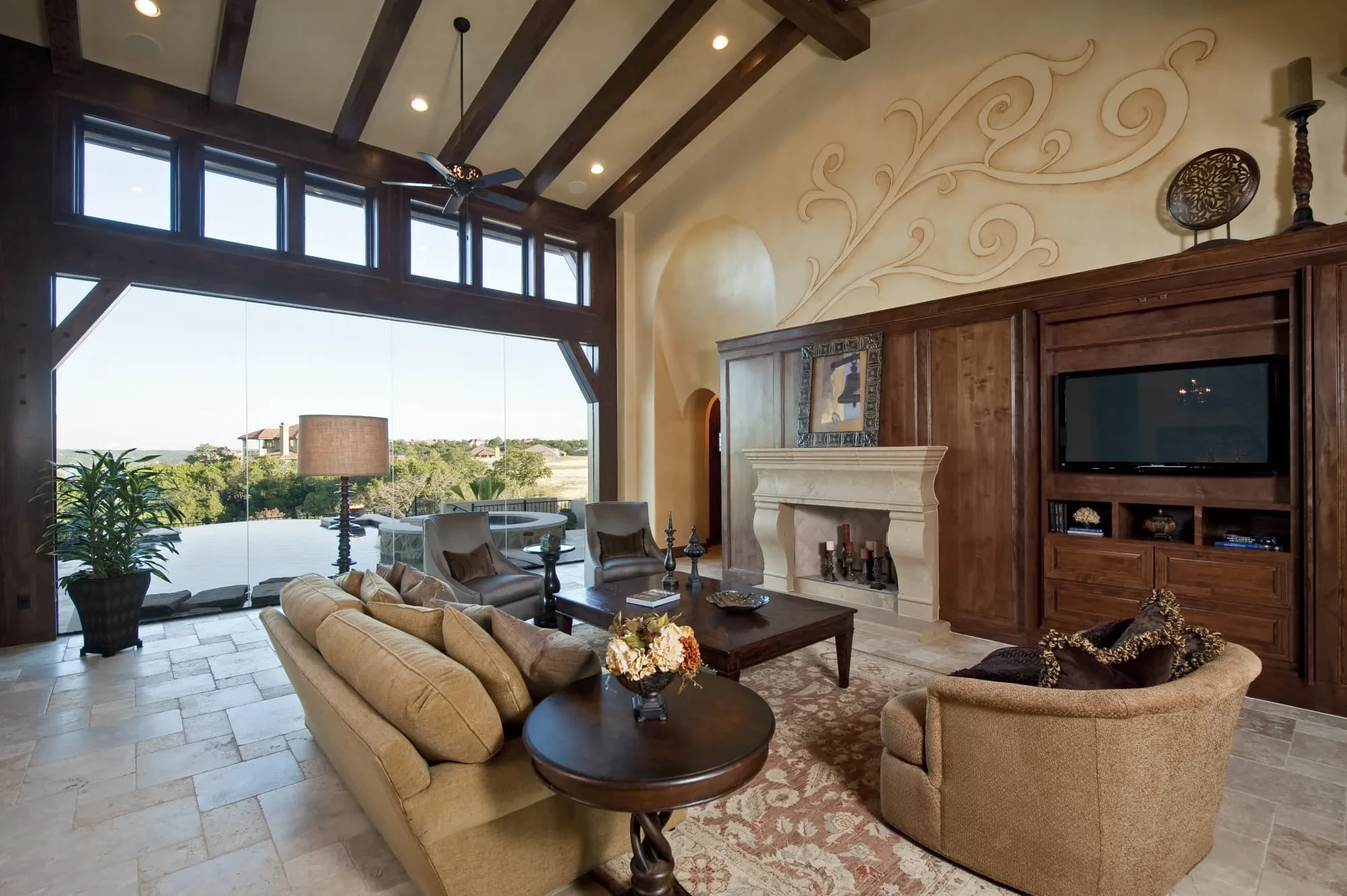 Great room with sculpted plaster scroll above the fireplace and built-in TV cabinet, Modern Mediterranean Parade Home