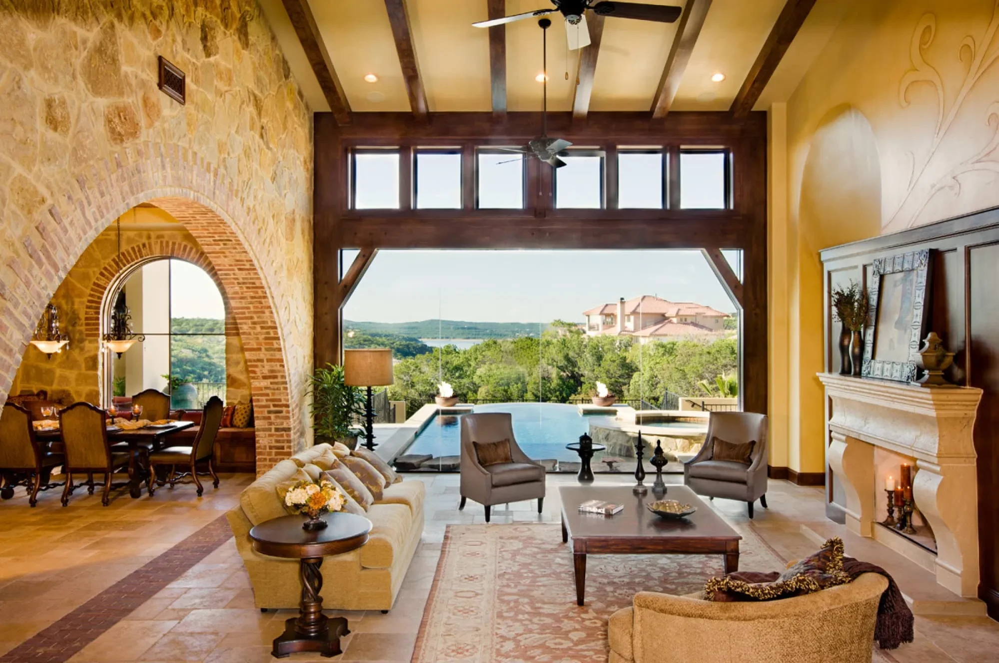 Great room view through the glass wall to the infinity pool and wooded hills, Modern Mediterranean Parade Home