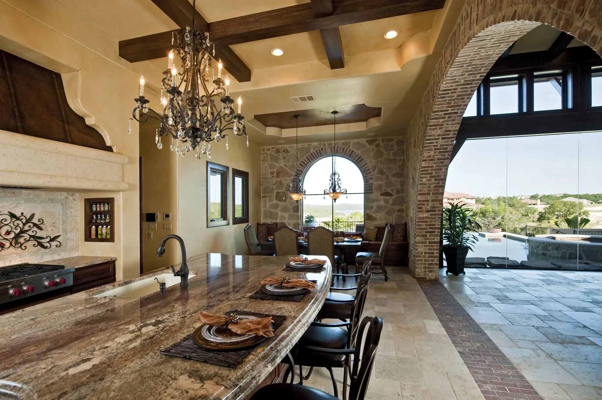 Kitchen island with granite top and chandelier, dining nook and pool view beyond, Modern Mediterranean Parade Home