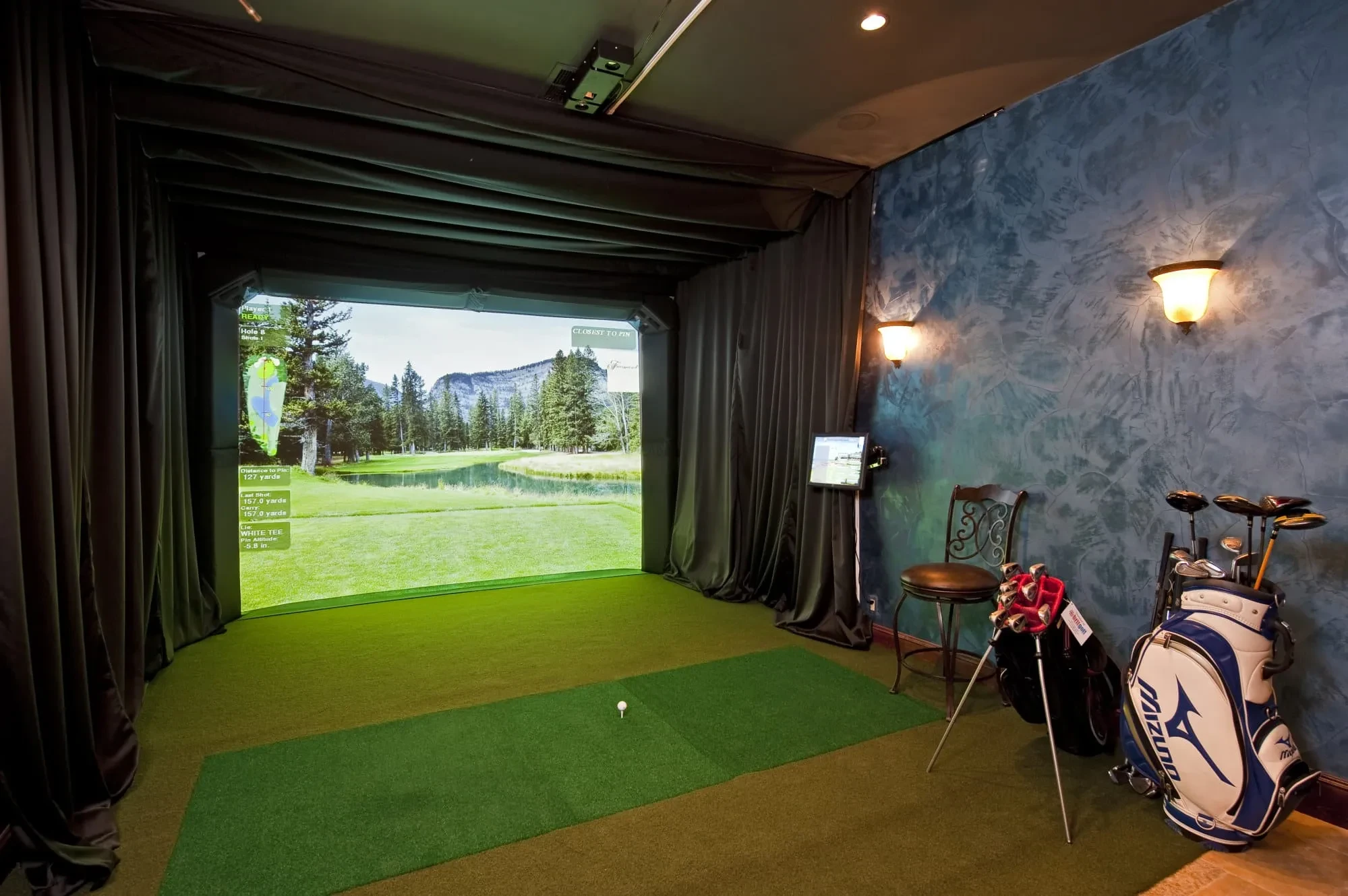 Indoor golf simulator room with projection screen and textured teal wall, Modern Mediterranean Parade Home
