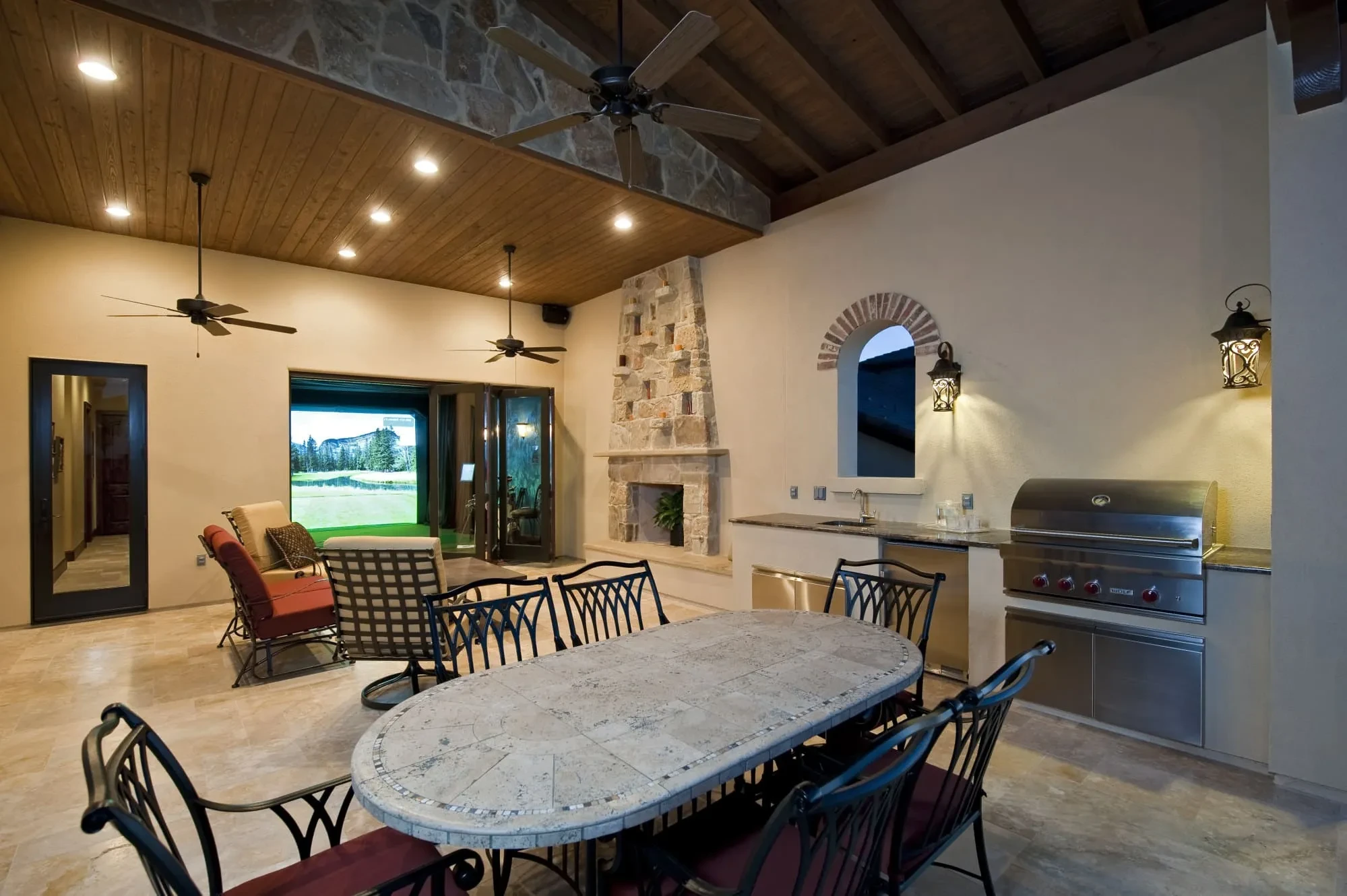 Covered outdoor living area with stone fireplace, grill and oval dining table, Modern Mediterranean Parade Home