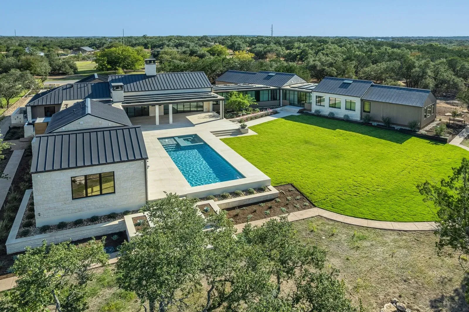 Custom luxury ranch home integrated with Texas terrain, trees, pool, and natural landscape preserved
