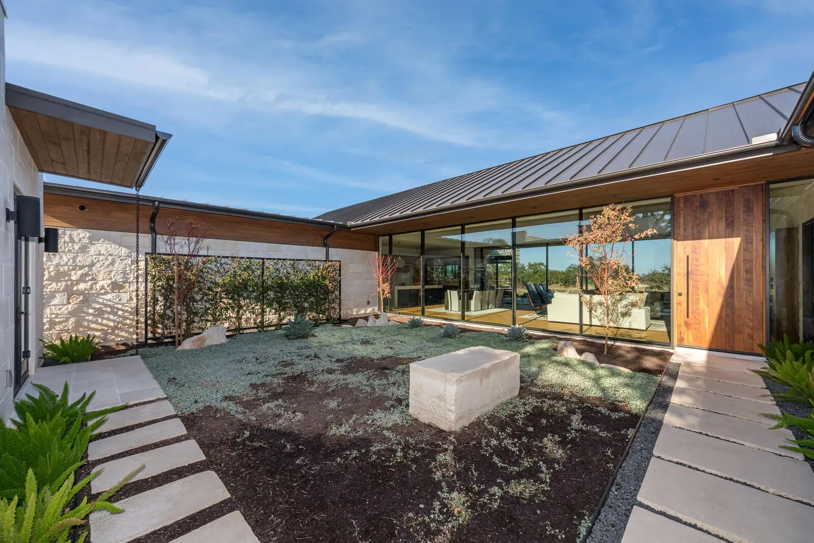 Single-story luxury home wrapped around a courtyard with walls of glass opening to the Hill Country