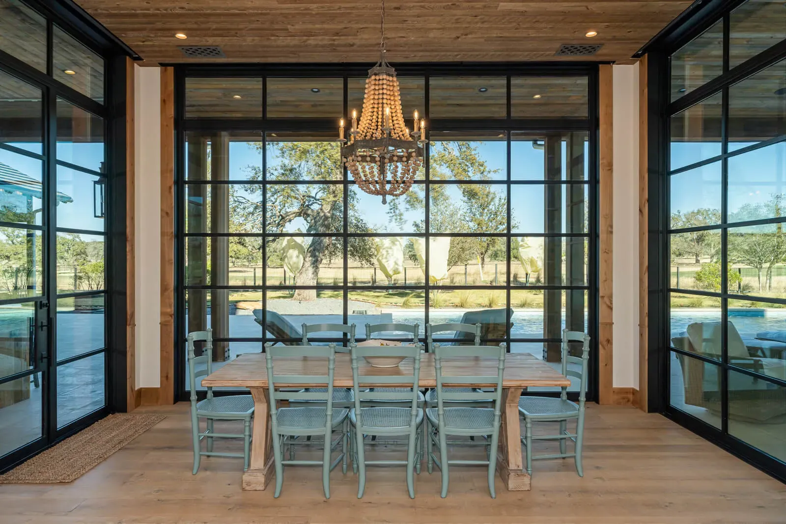 Dining room in Austin home with framed views through grid windows and chandelier.