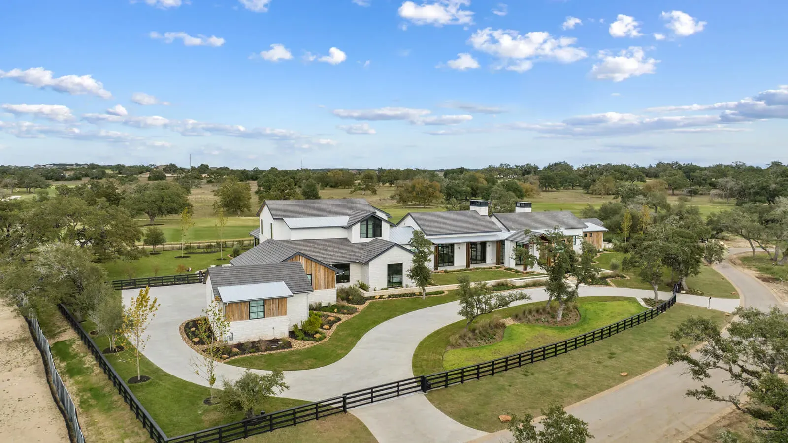Aerial of Hill Country estate with shaded trees and fencing.