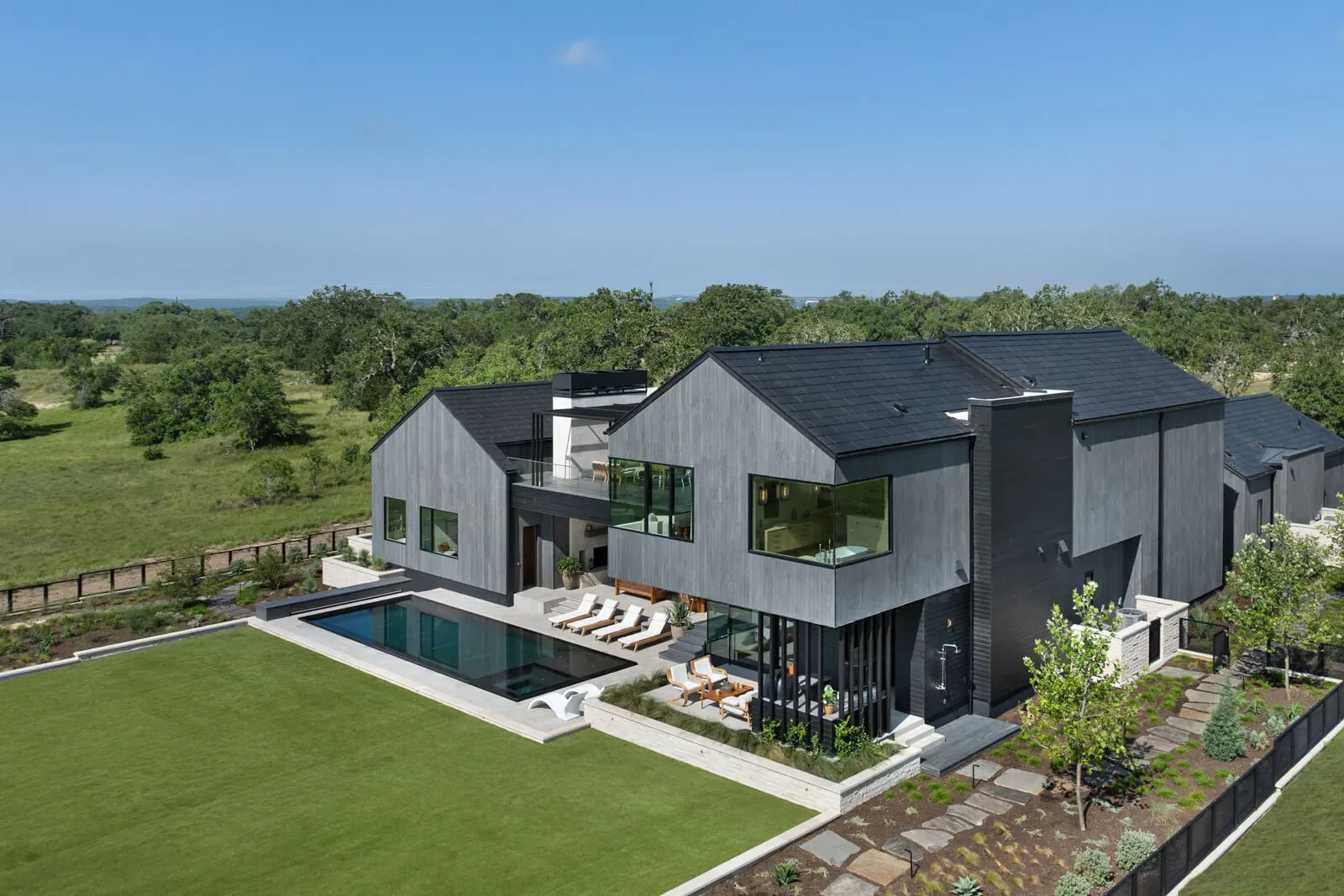 Modern Hill Country home with pool, lawn, and fenced yard.