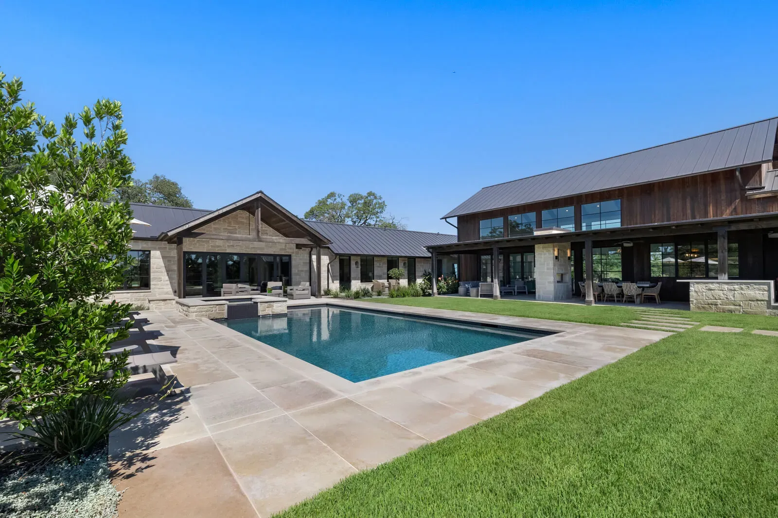 Hill Country pool and patio next to a modern Texas farmhouse in Austin