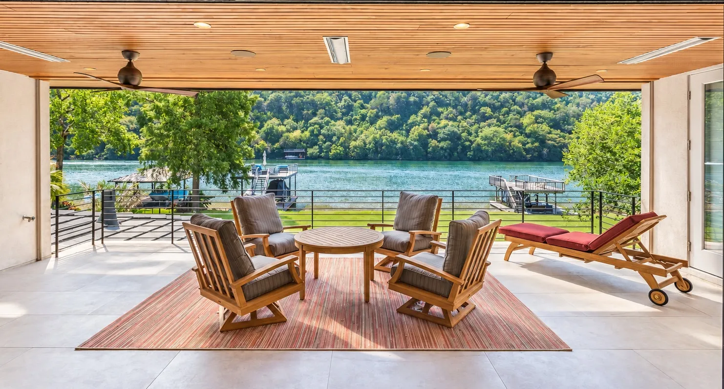 Covered lakeside terrace with teak seating opening onto Lake Austin, in a Jenkins Design Build custom home