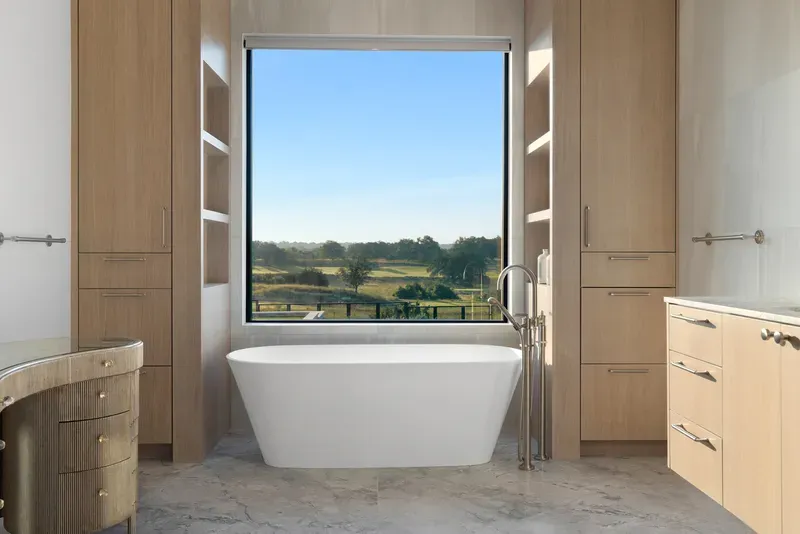 Luxury primary suite in Austin with freestanding soaking tub and panoramic Hill Country view