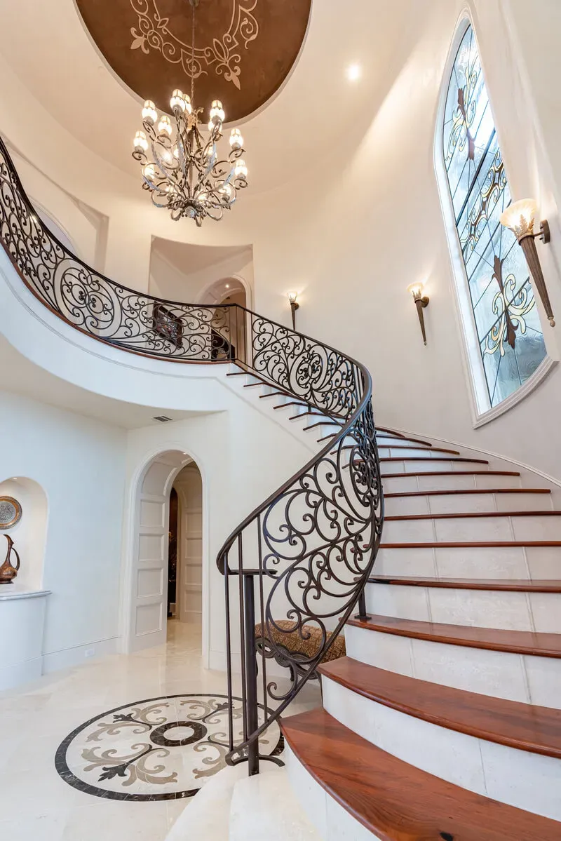 spiral staircase with ornate railing and stone inlay floor