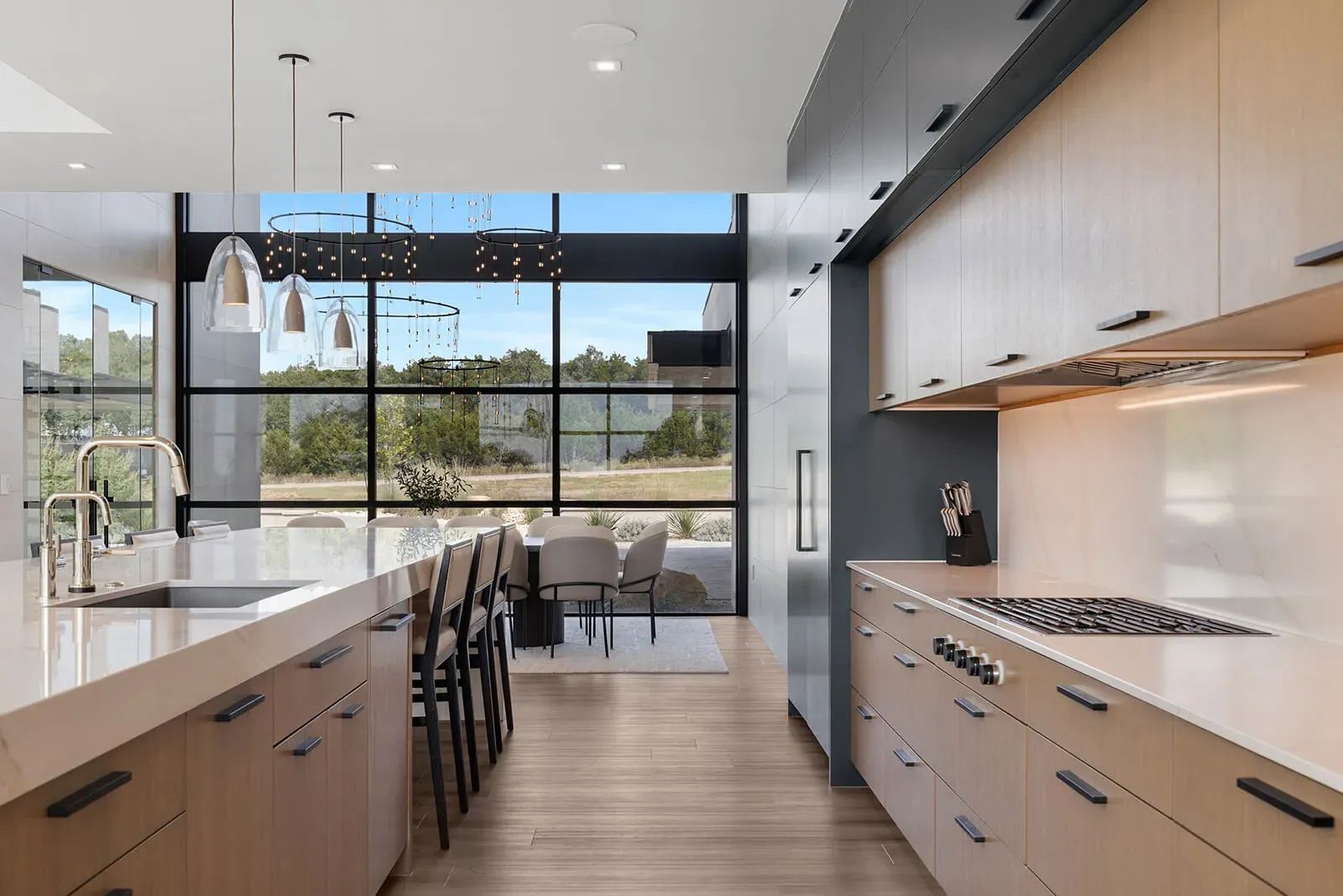 Modern Austin estate kitchen with large island, floor-to-ceiling windows, and dining area beyond