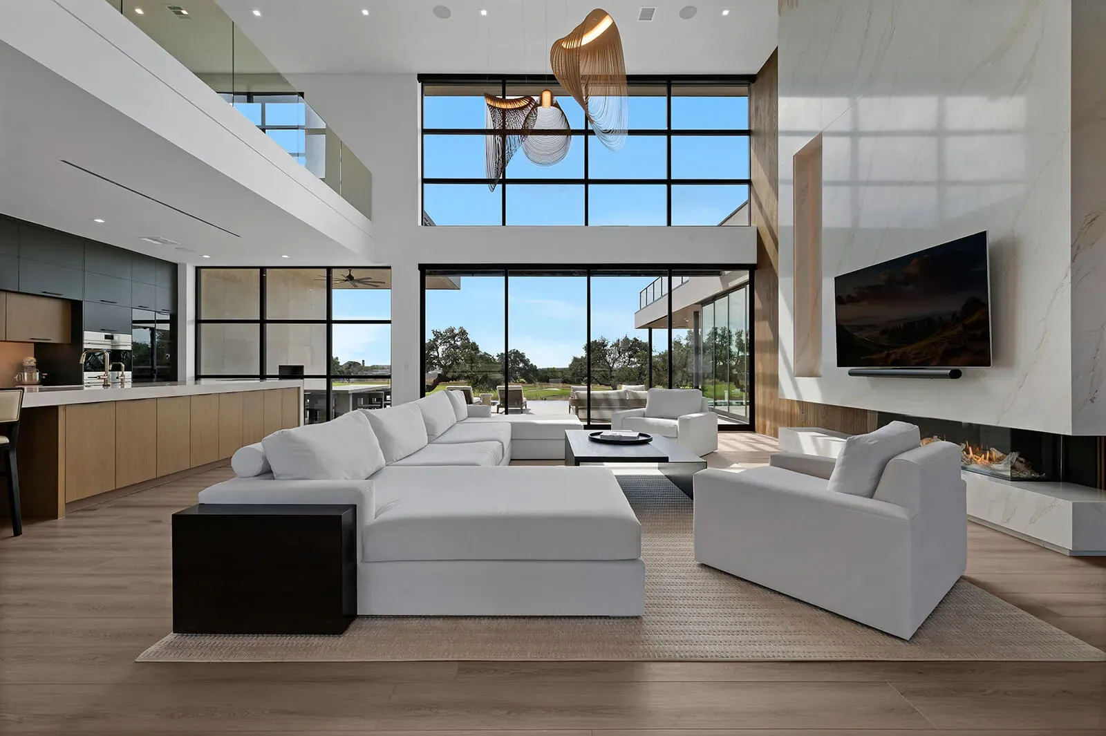 Modern open-concept living room in a luxury Austin home with large windows, contemporary furnishings, and natural light