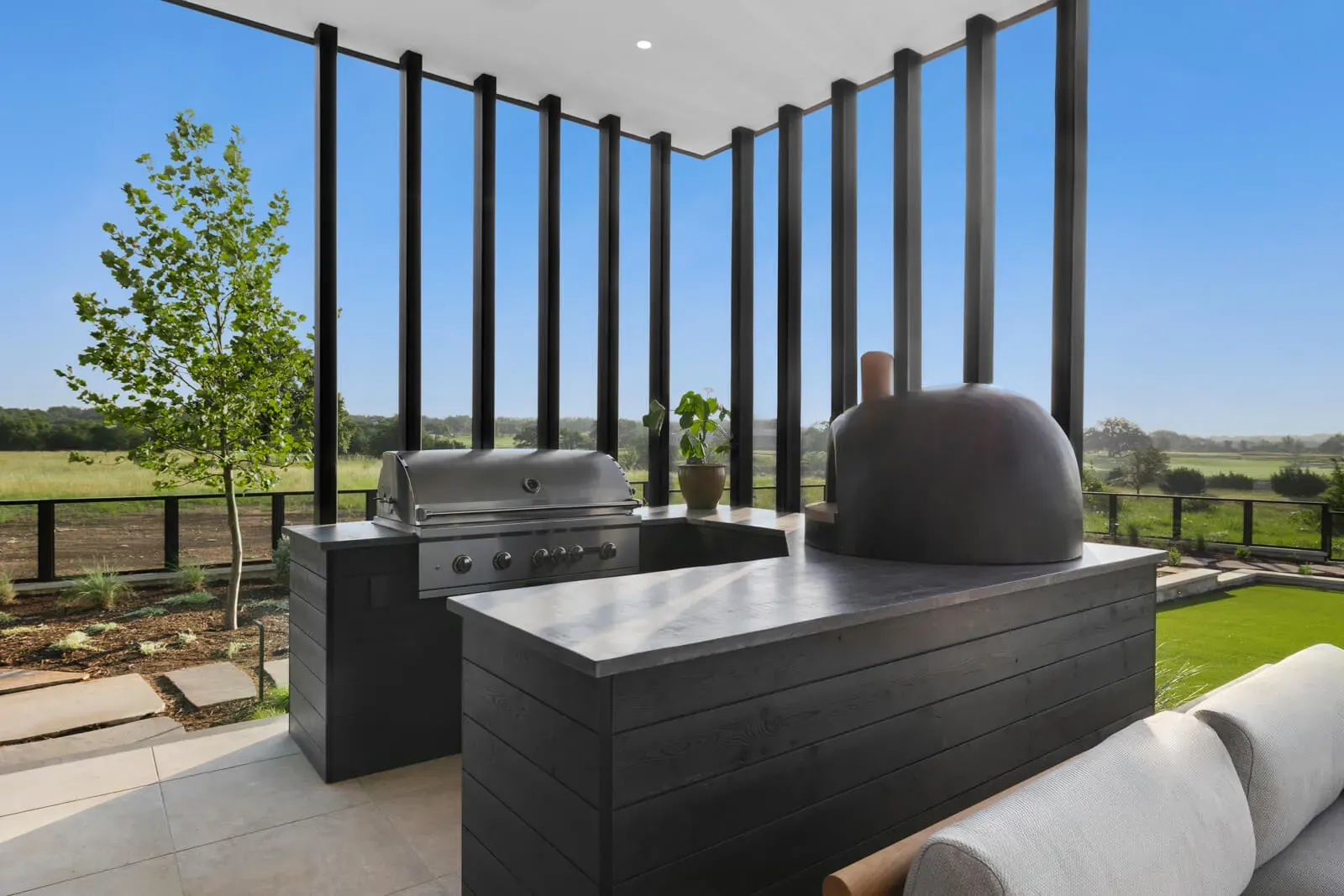 Modern outdoor kitchen with grill and pizza oven overlooking the Texas Hill Country.