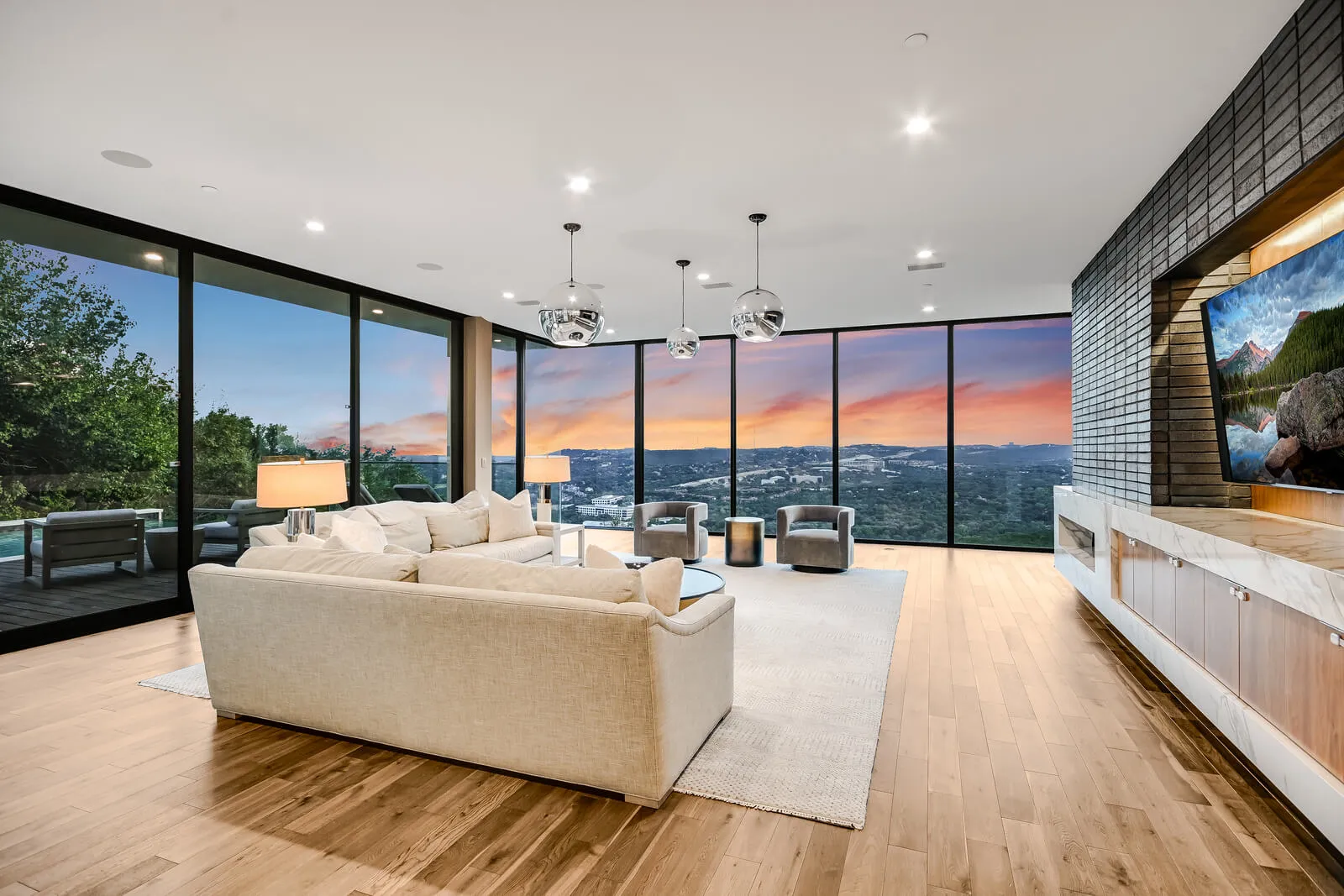 Modern Austin living room with full glass window wall overlooking Hill Country sunset.