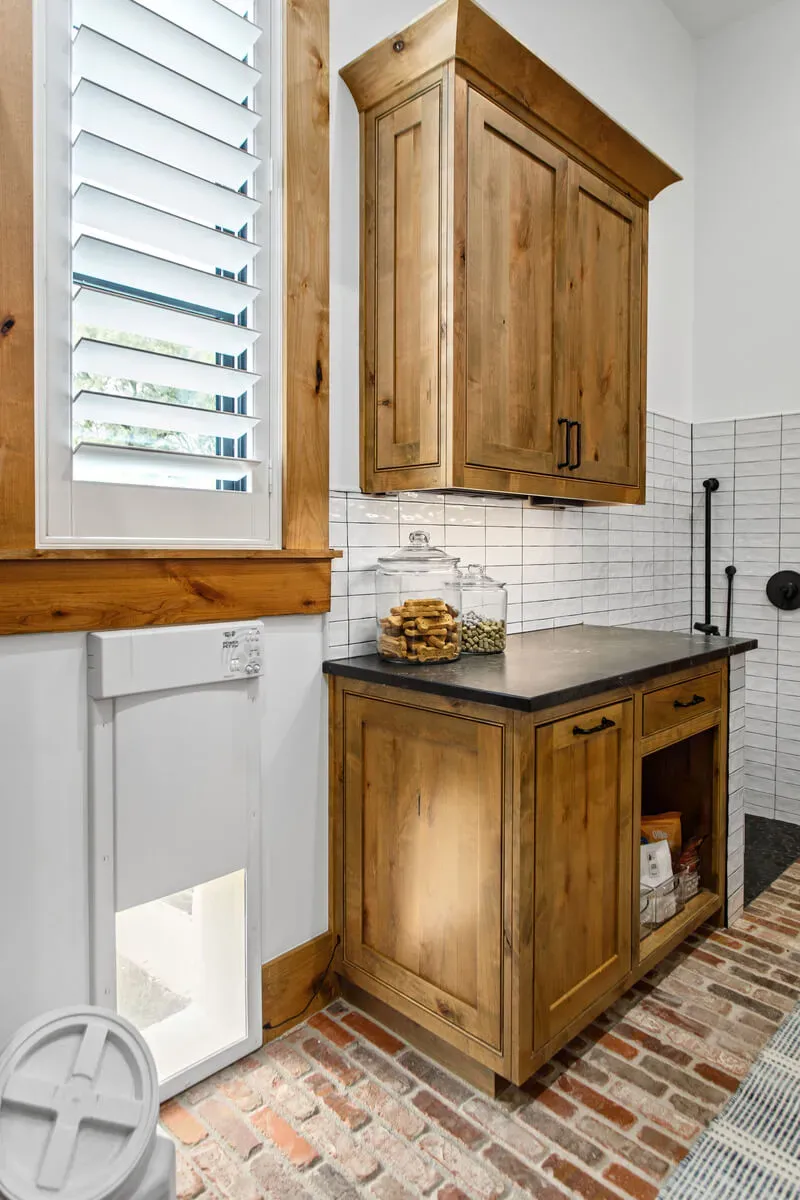 Mudroom with wood cabinetry, pet door, and treat jars.