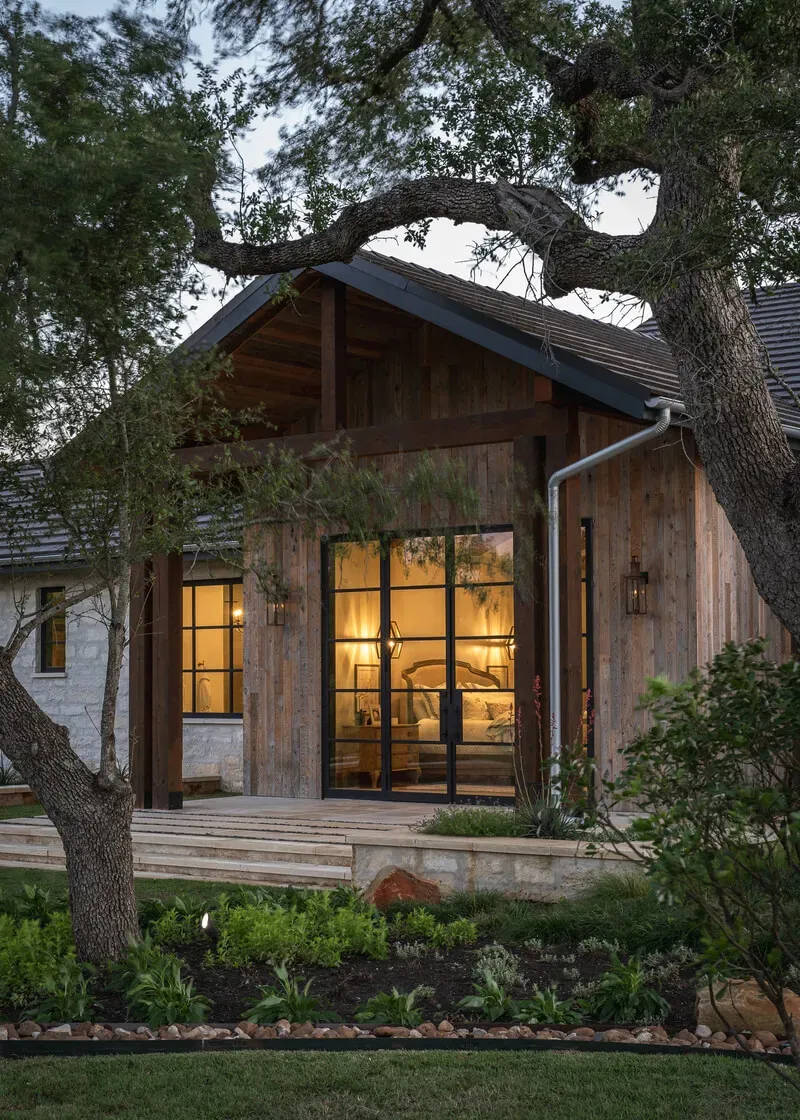 Rustic casita exterior with reclaimed wood accents and steel-framed doors set against the Texas Hill Country landscape