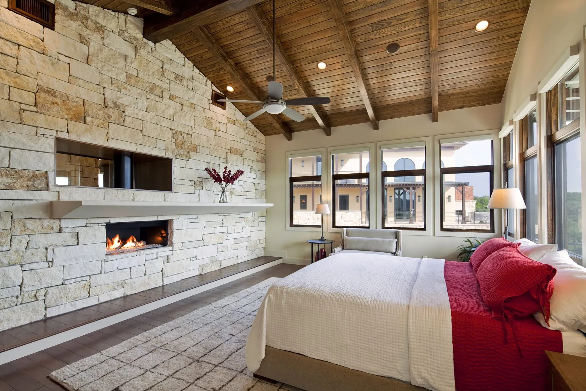 Austin luxury primary suite with floor-to-ceiling limestone fireplace and vaulted wood ceiling