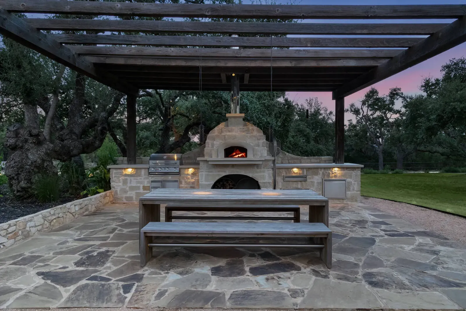 Rustic outdoor kitchen with a stone pizza oven in Austin, TX
