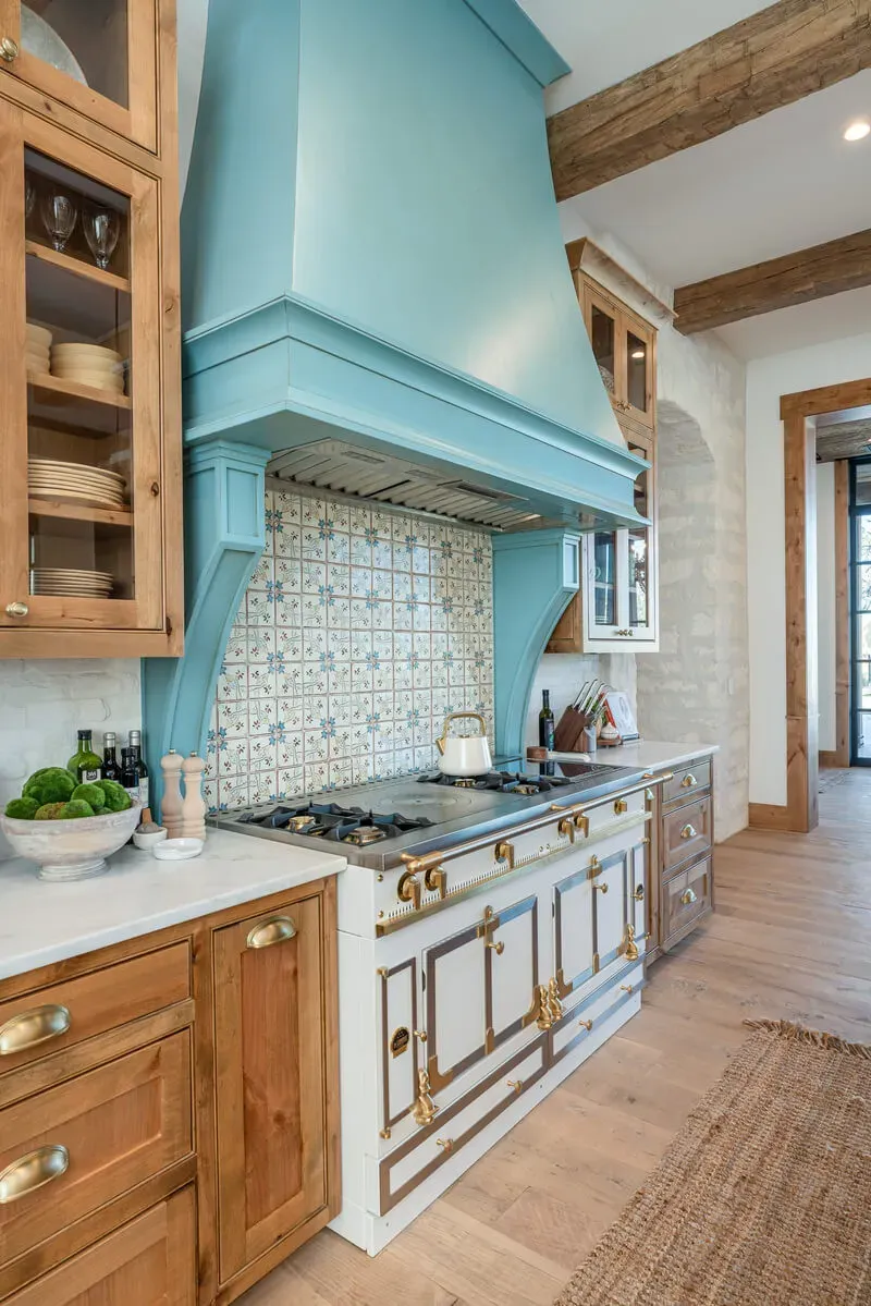 Custom blue range hood integrated with symmetrical display cabinetry
